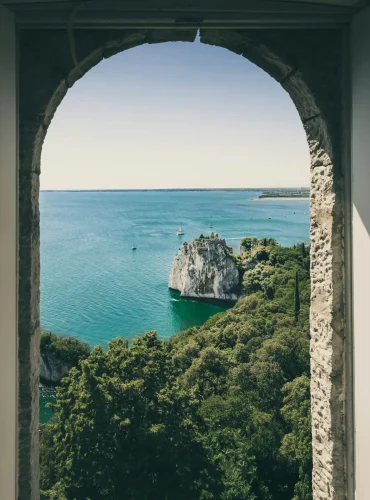 Idyllic view of Duino Cliffs and sea through arched window in Italy, perfect for travel inspiration.